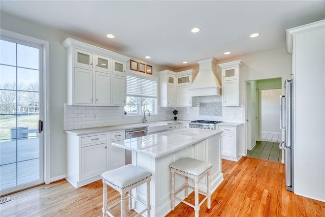 kitchen featuring a kitchen island, custom exhaust hood, a breakfast bar area, and white cabinetry