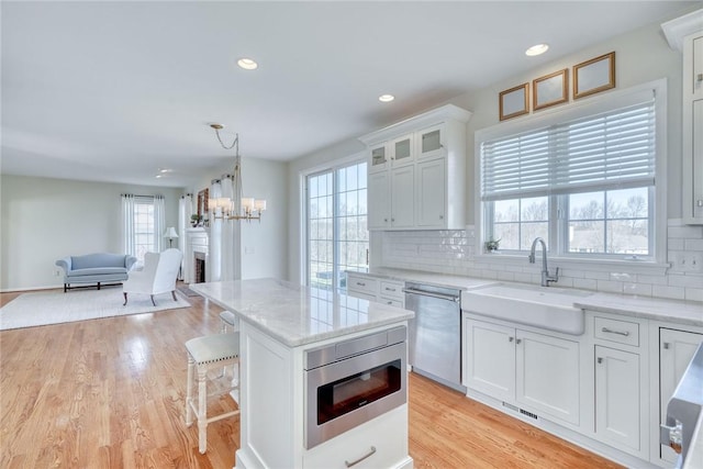 kitchen with a sink, backsplash, appliances with stainless steel finishes, and white cabinetry