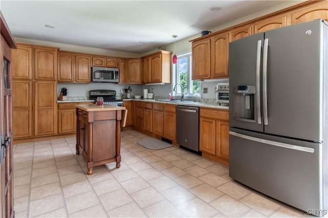 kitchen featuring pendant lighting, a sink, stainless steel appliances, brown cabinetry, and light countertops