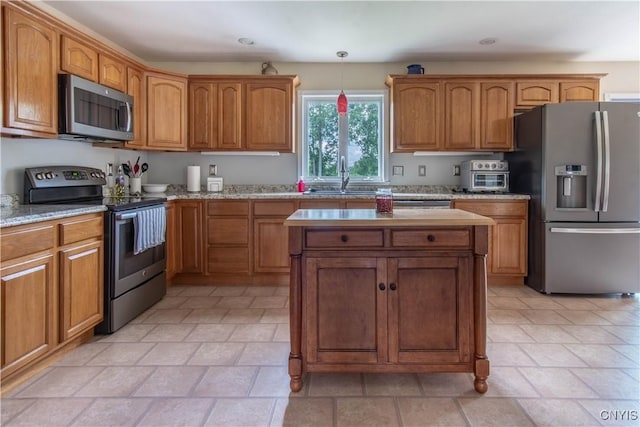 kitchen with a sink, stainless steel appliances, brown cabinets, and hanging light fixtures