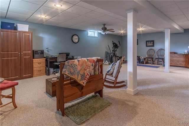 living room featuring light carpet, a drop ceiling, and decorative columns