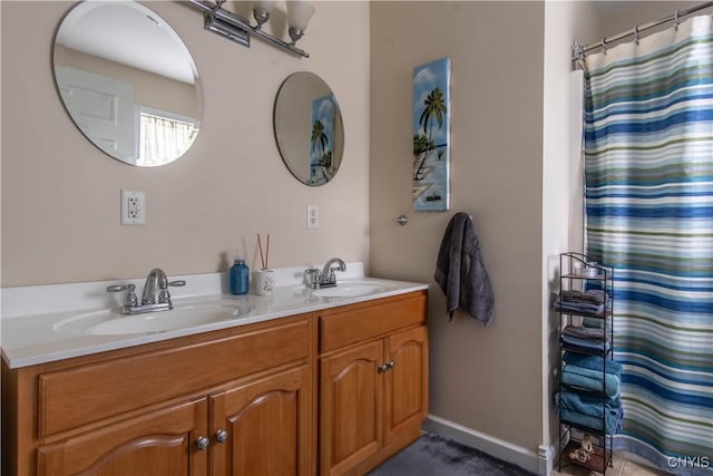 full bathroom with curtained shower, double vanity, baseboards, and a sink