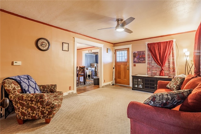 carpeted living room featuring baseboards, a textured ceiling, ornamental molding, and a ceiling fan