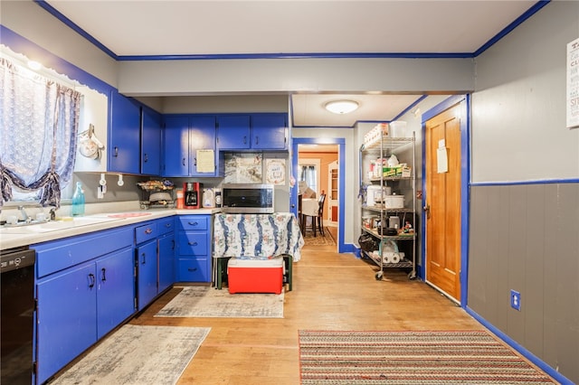 kitchen featuring light wood-style flooring, stainless steel microwave, black dishwasher, wainscoting, and light countertops