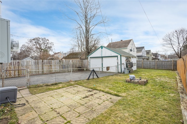 view of yard with a fenced backyard, a detached garage, a residential view, and an outdoor structure