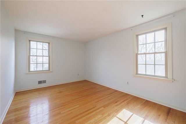 spare room featuring visible vents, light wood-type flooring, and baseboards