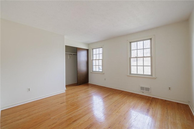 unfurnished bedroom featuring light wood finished floors, visible vents, baseboards, a closet, and a textured ceiling