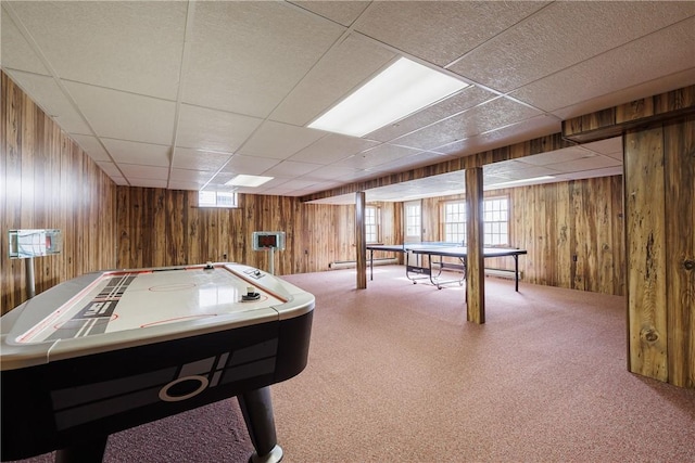 recreation room featuring a drop ceiling and wood walls