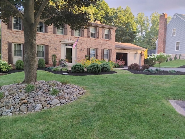 colonial-style house with a front lawn, an attached garage, and brick siding