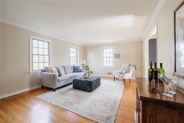 living area with visible vents, baseboards, crown molding, and light wood-style floors