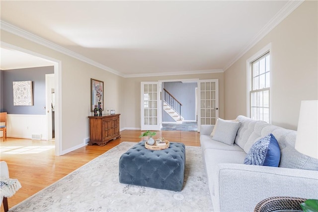 living area featuring stairway, french doors, light wood-style floors, and ornamental molding