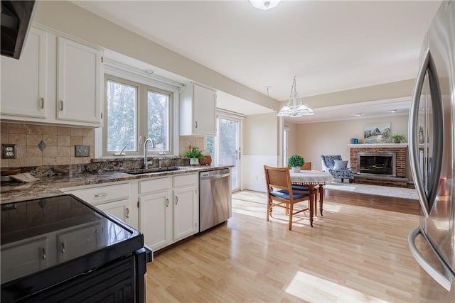 kitchen featuring stone counters, white cabinets, appliances with stainless steel finishes, and a sink