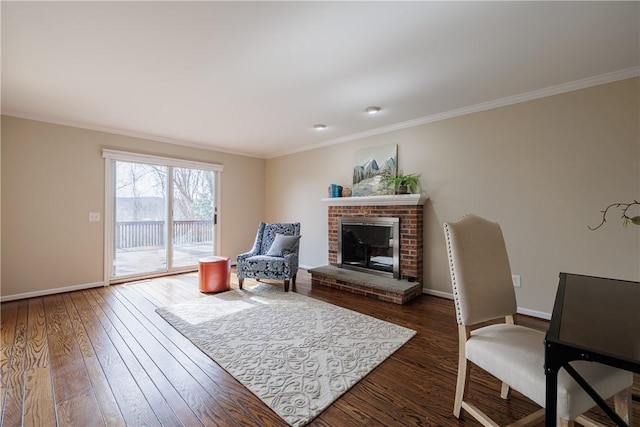 living area featuring ornamental molding, a fireplace, baseboards, and wood-type flooring