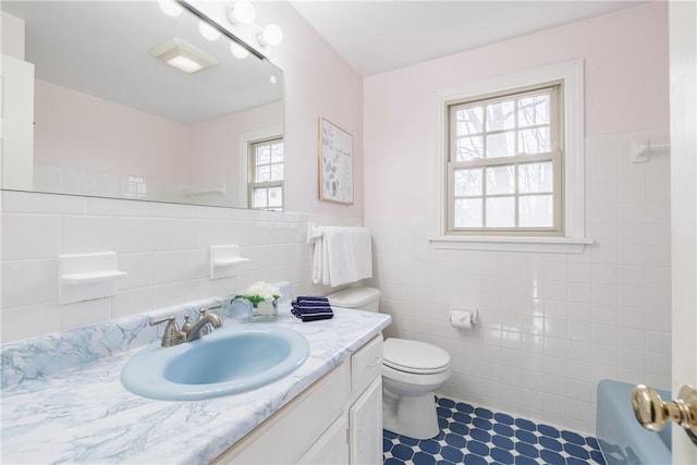 bathroom featuring vanity, tile walls, toilet, and a wainscoted wall