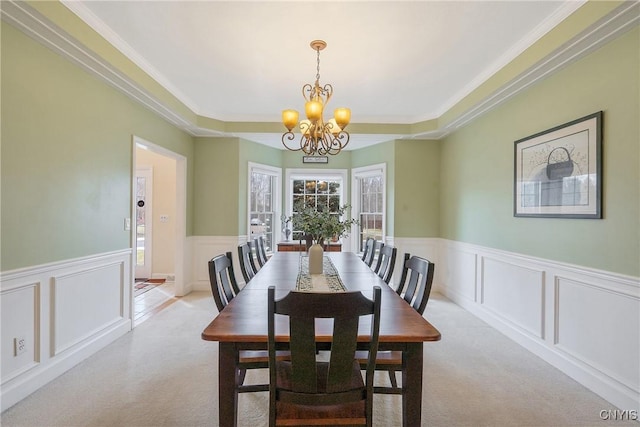 dining area with a chandelier, a wainscoted wall, ornamental molding, carpet flooring, and a decorative wall