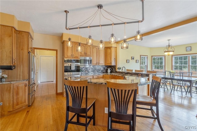 kitchen with decorative backsplash, appliances with stainless steel finishes, a kitchen breakfast bar, and a sink