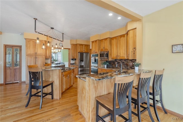 kitchen featuring dark stone counters, tasteful backsplash, appliances with stainless steel finishes, and a peninsula