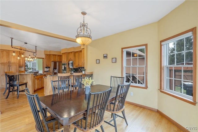 dining space with light wood-type flooring and baseboards