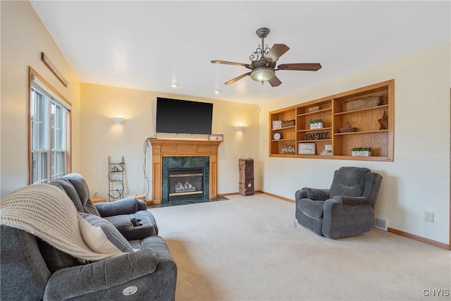 carpeted living area with a premium fireplace, baseboards, and a ceiling fan