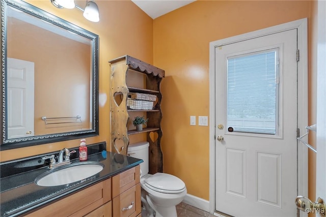 bathroom featuring baseboards, toilet, vanity, and tile patterned flooring