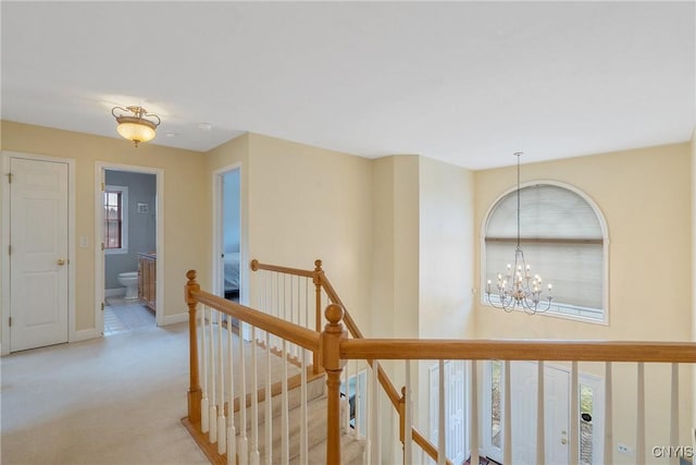 corridor with carpet, an upstairs landing, baseboards, and a chandelier