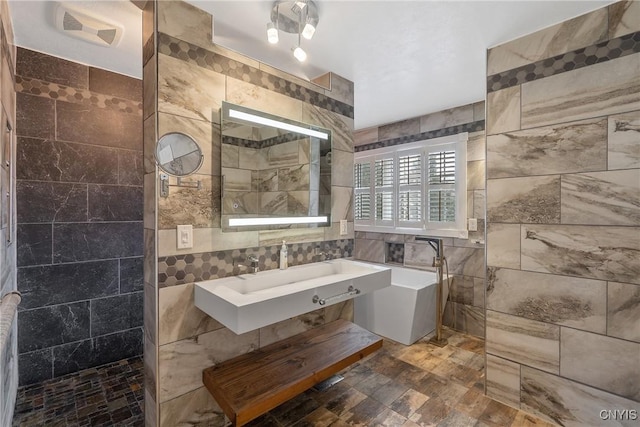 bathroom featuring a sink, tile walls, walk in shower, and a freestanding tub