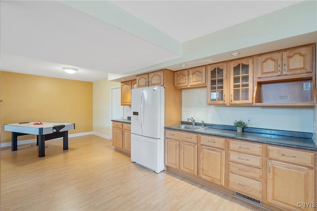 kitchen featuring visible vents, glass insert cabinets, light wood-style flooring, white refrigerator with ice dispenser, and a sink