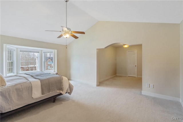 bedroom featuring lofted ceiling, baseboards, arched walkways, and light carpet