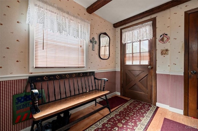 entrance foyer featuring beam ceiling, wood finished floors, wainscoting, and wallpapered walls