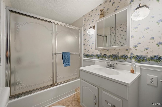 full bath featuring wallpapered walls, a textured ceiling, shower / bath combination with glass door, tile patterned flooring, and vanity