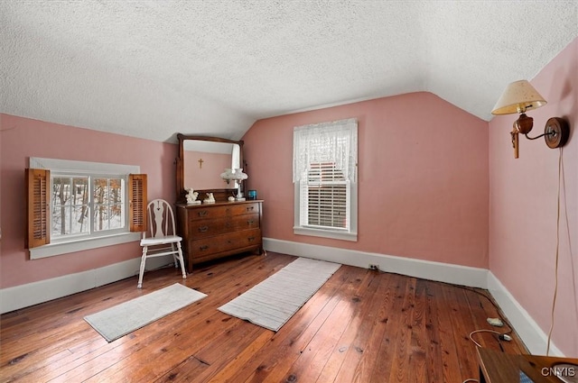 additional living space featuring hardwood / wood-style flooring, baseboards, and vaulted ceiling