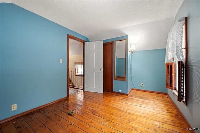 unfurnished bedroom with baseboards, lofted ceiling, and hardwood / wood-style floors