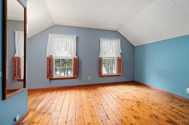 bonus room with vaulted ceiling, a textured ceiling, baseboards, and hardwood / wood-style floors