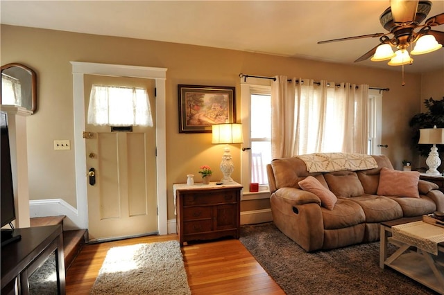 living area featuring ceiling fan, baseboards, and wood finished floors