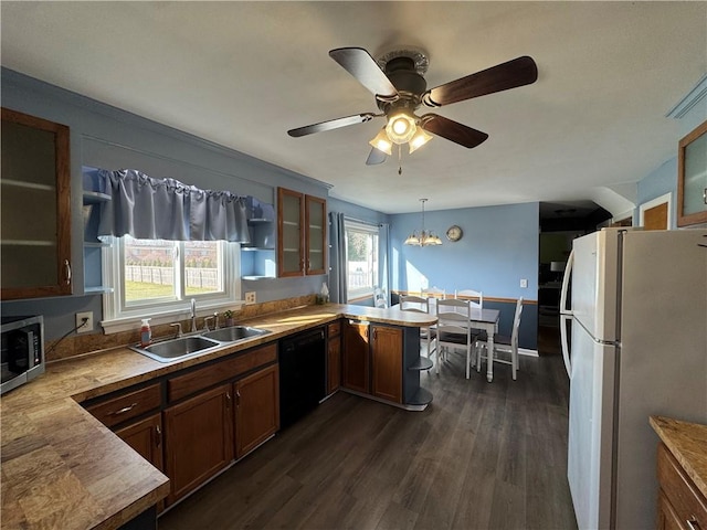 kitchen with a peninsula, freestanding refrigerator, a sink, dishwasher, and stainless steel microwave