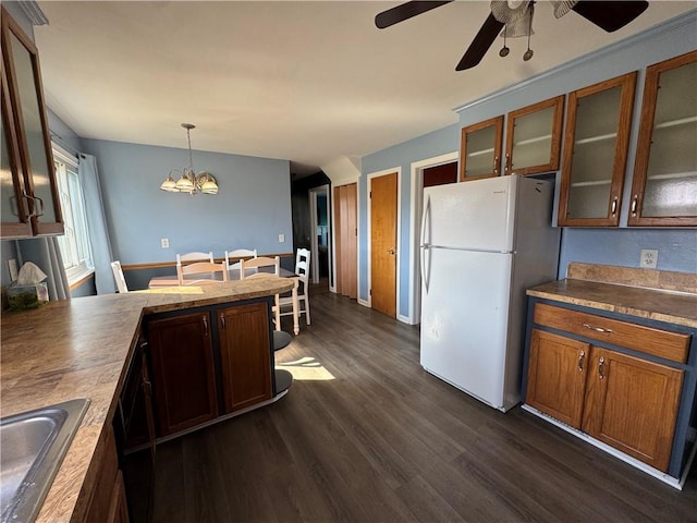 kitchen featuring dark wood finished floors, freestanding refrigerator, a sink, glass insert cabinets, and pendant lighting