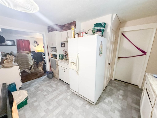 kitchen with light floors, white cabinets, white refrigerator with ice dispenser, and light countertops