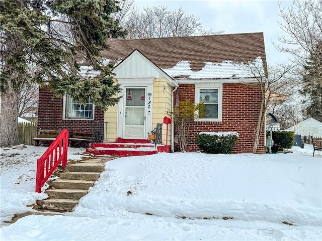 view of front of home featuring brick siding and roof with shingles