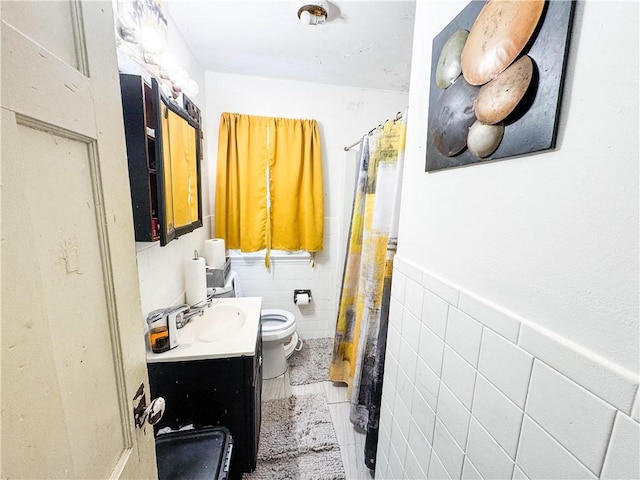 bathroom featuring vanity, wainscoting, curtained shower, tile walls, and toilet