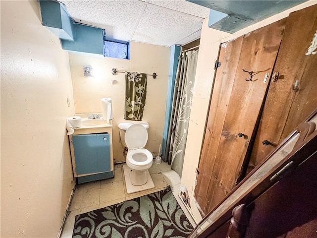 bathroom with vanity, curtained shower, toilet, and a paneled ceiling