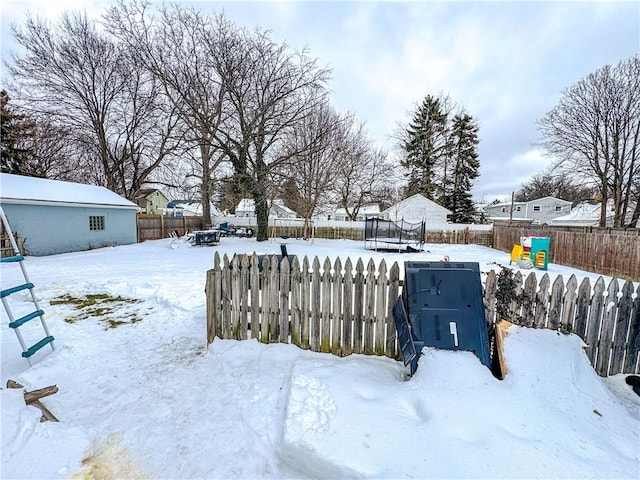 yard covered in snow featuring a fenced backyard and a trampoline