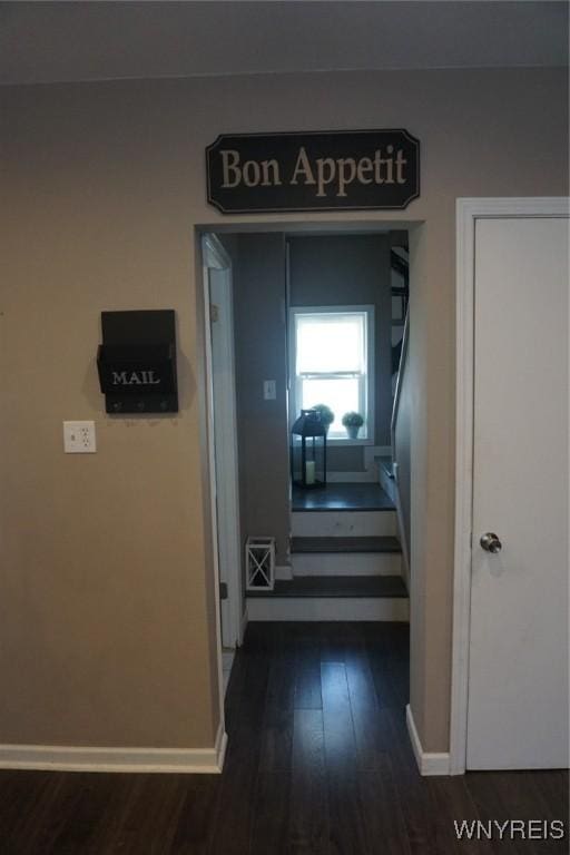 corridor with visible vents, baseboards, and dark wood-style flooring