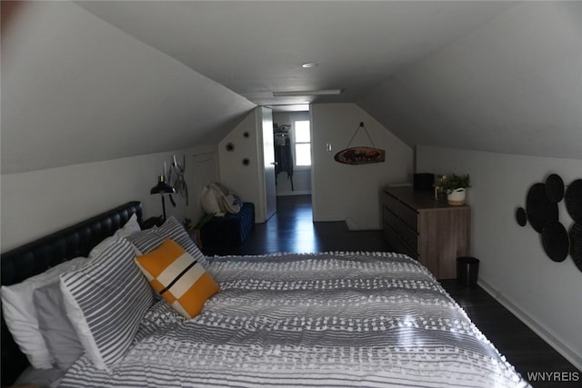 bedroom with vaulted ceiling, baseboards, and wood finished floors