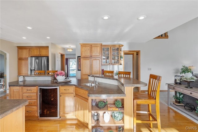 kitchen with stainless steel fridge with ice dispenser, beverage cooler, a breakfast bar, light wood-style flooring, and a sink