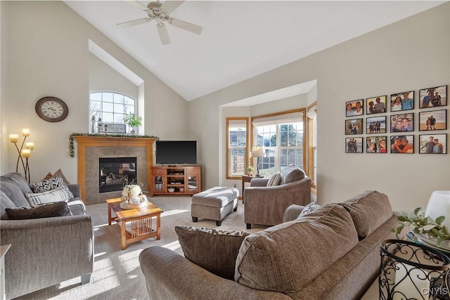 living area featuring a tiled fireplace, lofted ceiling, carpet flooring, and ceiling fan