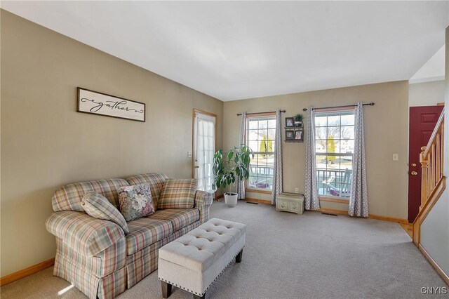 living room featuring stairway, baseboards, light colored carpet, and visible vents