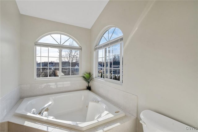 full bathroom featuring toilet, lofted ceiling, and a whirlpool tub