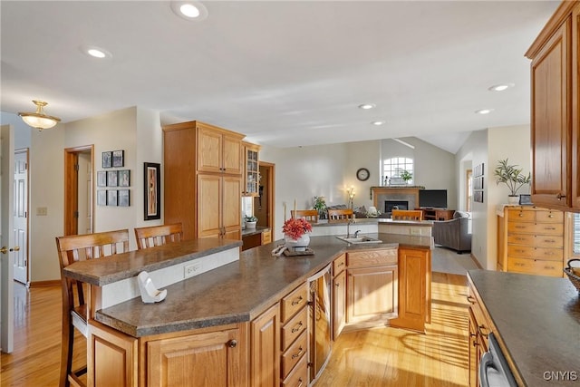 kitchen featuring dark countertops, light wood finished floors, a center island, and a sink