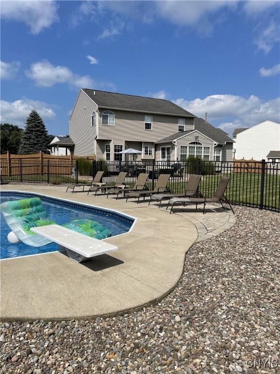 view of swimming pool featuring a patio area, a fenced in pool, a diving board, and fence