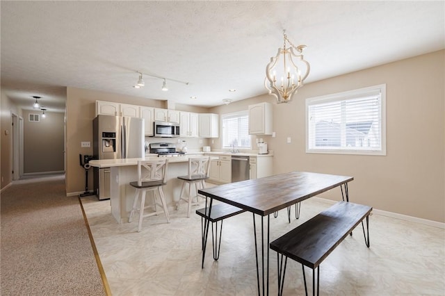 dining area with an inviting chandelier, baseboards, and a textured ceiling